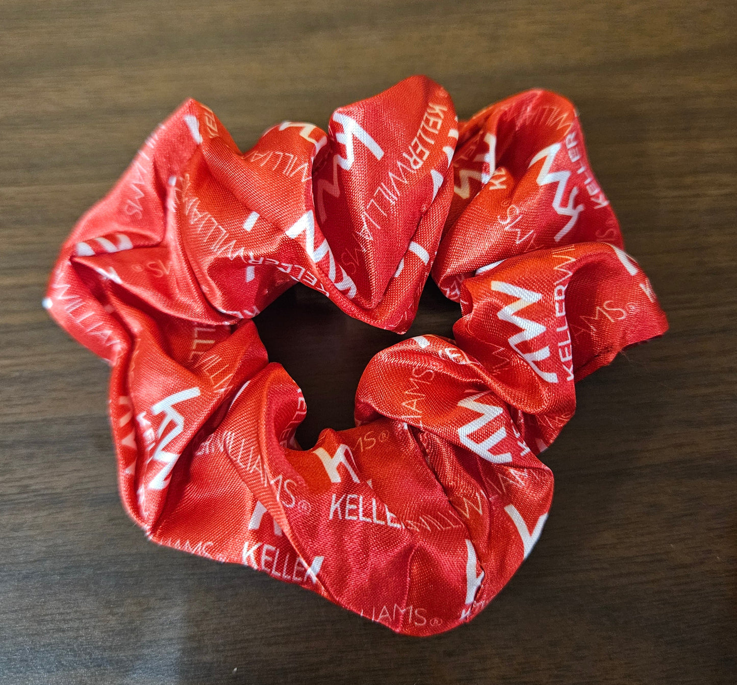 Red scrunchie with white text on a wooden surface